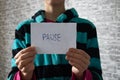 The word pause is written on a piece of paper that the quarantined girl is holding