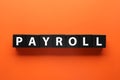 Word Payroll made with black wooden cubes on orange background, flat lay Royalty Free Stock Photo