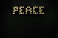 Word Peace made of 9 mm ammo on black wooden desk with copy space, golden bullets