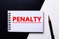 The word PENALTY is written on a black and white background near a pen. Financial concept