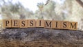 The word pessimism was created from wooden cubes. Photographed on the tree..