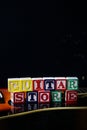 Word or phrase Guitar Store made with letter cubes, standing on guitar.