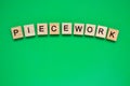 Word piecework. Top view of wooden blocks with letters on green surface Royalty Free Stock Photo