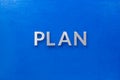 The word plan laid with silver metal letters on blue board in flat lay with central composition Royalty Free Stock Photo