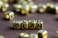 Word PLAN made from small golden letters on the brown background Royalty Free Stock Photo