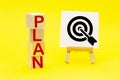 The word PLAN and sign stand on a yellow background. Hit exactly on center. Tactics of advertising targeting. advertise campaigns Royalty Free Stock Photo