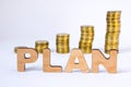 Word plan of three-dimensional letters is in foreground with growth columns of coins on blurred background. Monetary plan concept