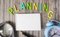The word Planning consists of colored letters, next to a notepad for writing, a magnifier and an alarm clock Royalty Free Stock Photo