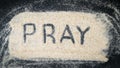 Word PRAY written on white sand