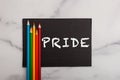 The word PRIDE painted on black sign with primary rainbow colored pencils Royalty Free Stock Photo