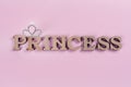 Word Princess abstract wooden letters. Pink background with sparkling crown. Royalty Free Stock Photo