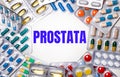 The word PROSTATA is written on a light background surrounded by multi-colored packages with pills. Medical concept