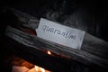 The word `quarantine` is written on a piece of paper lying in a fire in smoke. Dark photo in dark colors