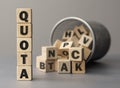 The word QUOTA made from wooden cubes. Shallow depth of field on the cubes