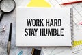 Word quotes of WORK HARD STAY HUMBLE on colorful memo papers with wooden background.