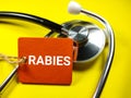 Word RABIES with stethoscope on yellow background.