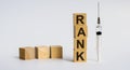 Word RANK written with wooden blocks, next to it is a syringe - a threat to life, a medical concept Royalty Free Stock Photo