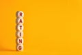 The word rating on wooden cubes against yellow background. Improvement in service rating and customer evaluation concept.