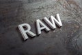 The word raw laid with silver metal letters on hot rolled steel sheet surface in diagonal perspective Royalty Free Stock Photo