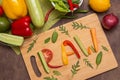 Word Raw written with letters from different raw vegetables, fruits and greens on wooden cutting board. Organic ingredients Royalty Free Stock Photo