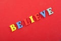 BELIEVE word on red background composed from colorful abc alphabet block wooden letters, copy space for ad text. Learning english Royalty Free Stock Photo