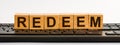 The word of REDEEM on building blocks concept. A row of wooden cubes with a word written in black font is located on a black