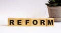 The word REFORM on wooden cubes on a light background near a flower in a pot. Defocus Royalty Free Stock Photo