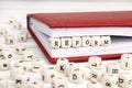 Word Reform written in wooden blocks in red notebook on white wooden table.