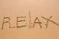 Word Relax hand written in the sand. Close up sand texture on beach in summer. Vacation, holiday concept Royalty Free Stock Photo