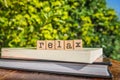 The word RELAX, letters cubes on books with green trees, nature background