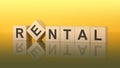 Word Rental made with wood blocks. text is written in black letters and is reflected in the mirror surface of the table, yellow Royalty Free Stock Photo