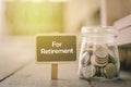 Word RETIREMENT on wooden signage and coin in jar .fade color effect wooden background with light effect