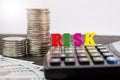 The word `risk` is folded with letters / calculator / stacks of coins and dollars. Close-up. The concept of business risk, economi