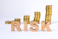 Word risk of three-dimensional letters is in foreground with growth columns of coins on blurred background. Risk concept for finan