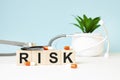 The word RISK is written on wooden cubes near a stethoscope on a wooden background. Medical concept Royalty Free Stock Photo