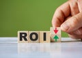 Word ROI symbol concept and hand turn wooden block and change red arrow to green Royalty Free Stock Photo