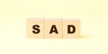 Word sad with black letters on wooden cubes against yellow Royalty Free Stock Photo
