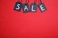 Word SALE made with black tags on red background, flat lay. Space for text