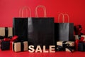 Word Sale made of wooden letters, shopping bags and gift boxes on red background. Black Friday Royalty Free Stock Photo