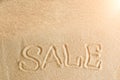 The word sale is painted in the sand. Beach background. Top view. The concept of summer, summer kanikkuly, vacation, holydays Royalty Free Stock Photo