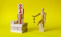 The word sale is written on wooden blocks. The wooden model of a man sits on the cubes and holds the keys. Royalty Free Stock Photo