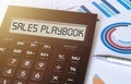 Word sales playbook on calculator. Business and finance concept