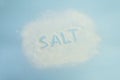 the word salt is written with salt on a blue table. Salt grain top view on blue background Royalty Free Stock Photo