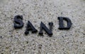 Word SAND made of black letters on the wet sand at the beach Royalty Free Stock Photo