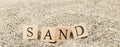 The word sand from wooden cubes. Close-up on the beach sand