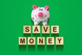 Word Save Money, composed of letters on wooden construction cubes with piggy bank. Green background, isolated Concept business, fi