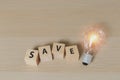 Word `save` on wooden cube blocks with Light bulb. eco environment.