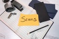 The word scams handwritten on paper laying on open account ledger checkbooks and random home office supplies Royalty Free Stock Photo