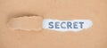 The word secret is standing on a ripped up paper