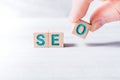The Word SEO Formed By Wooden Blocks And Arranged By Male Fingers On A White Table Royalty Free Stock Photo